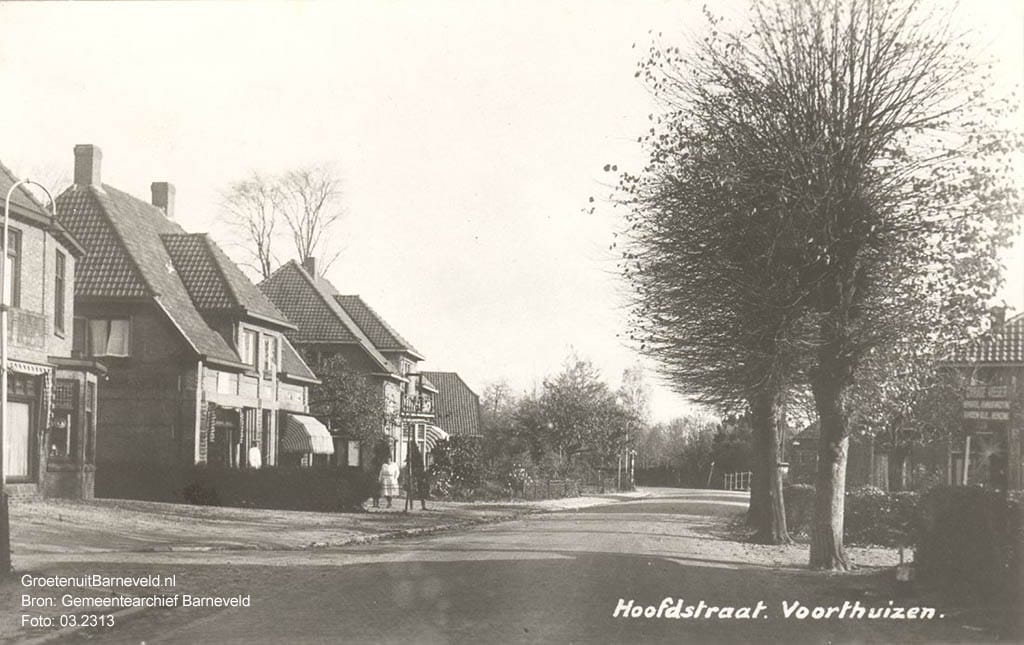 Verleden 1925/1940 - De Hoofdstraat in de richting van Apeldoorn. Rechts een bord met reclame voor garage Visser. Op de achtergrond de brug over de Ganzenbeek. - Voorthuizen